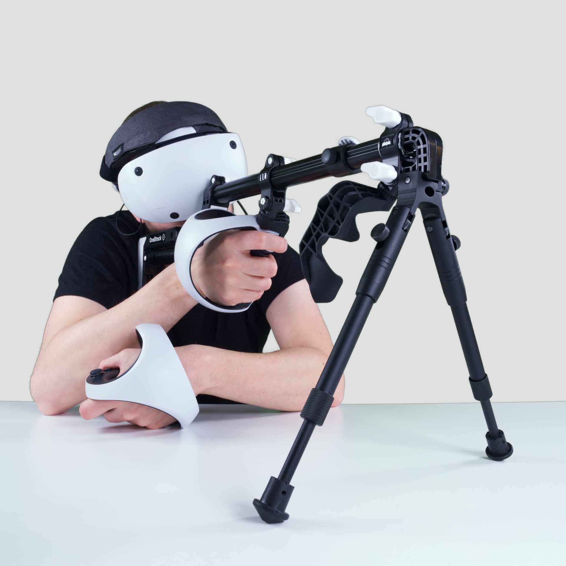 Man holding a Wield VR OneStock VR gunstock PSVR2 model with a bipod add-on mounted on a table